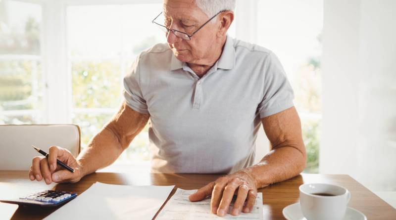 Worried senior man with tax documents at home